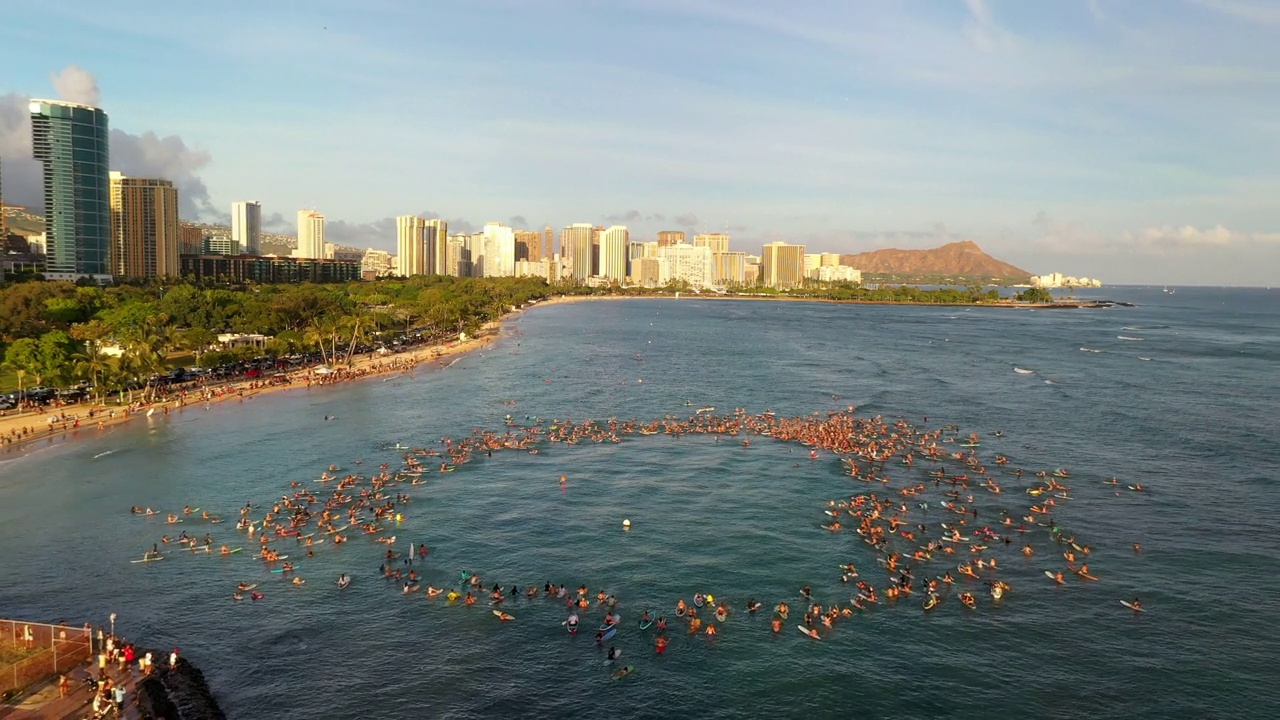 空中向后拍摄的人在冲浪板飞溅海水在城市-瓦胡岛，夏威夷视频素材