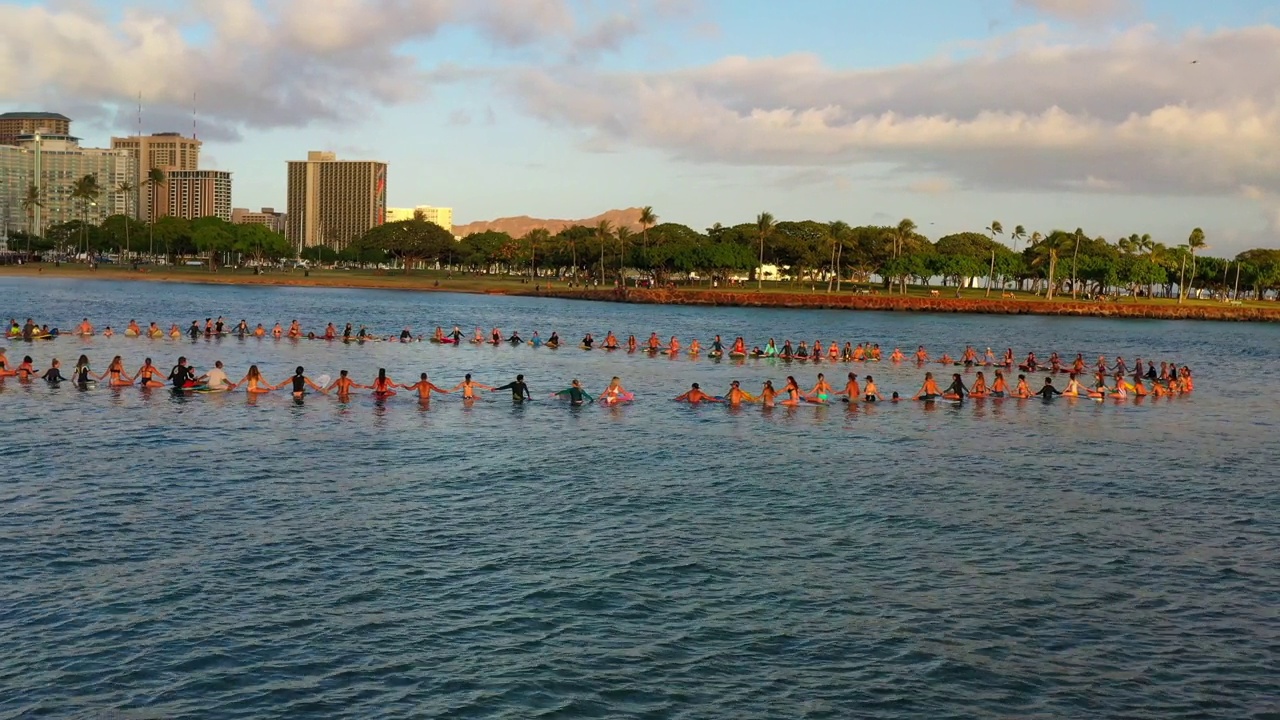 冲浪板上的冲浪者手牵手在云下的建筑物-夏威夷瓦胡岛视频素材