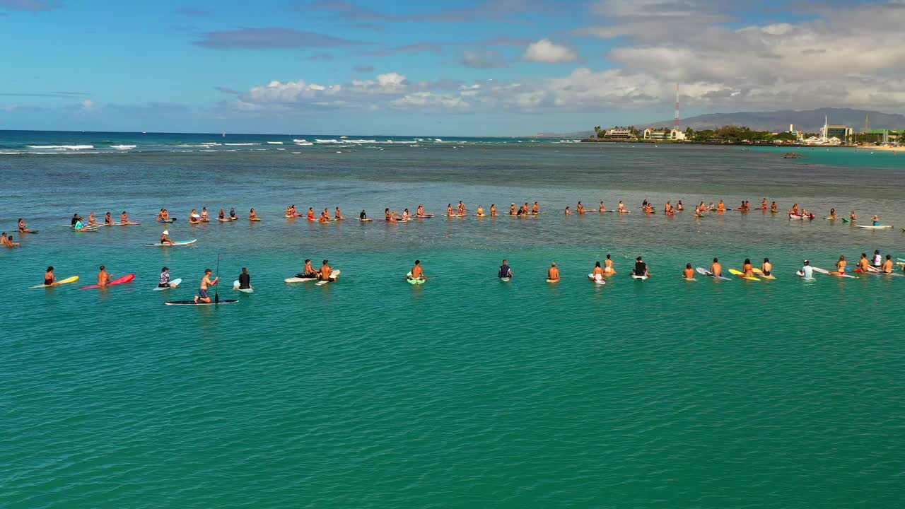 男人和女人在云层下的冲浪板漂浮在海上的平移镜头——夏威夷瓦胡岛视频素材