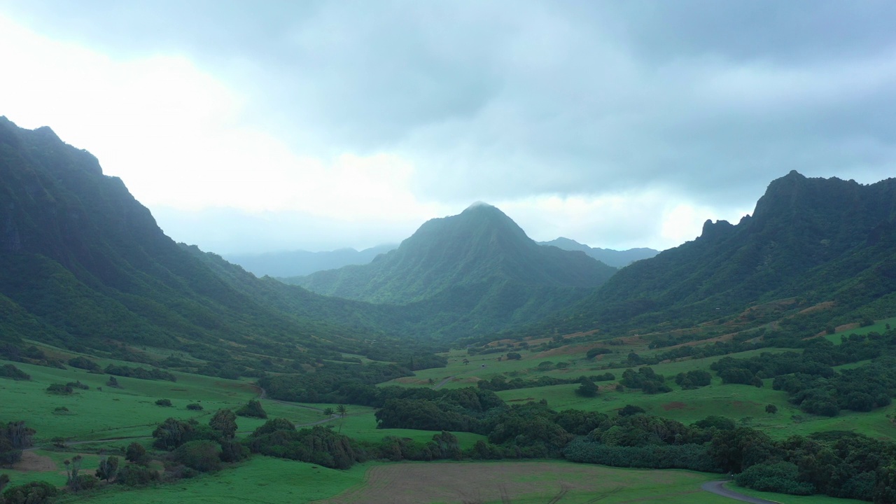 空中平移拍摄的绿色植物与景观对山在多云的天空-瓦胡岛，夏威夷视频素材