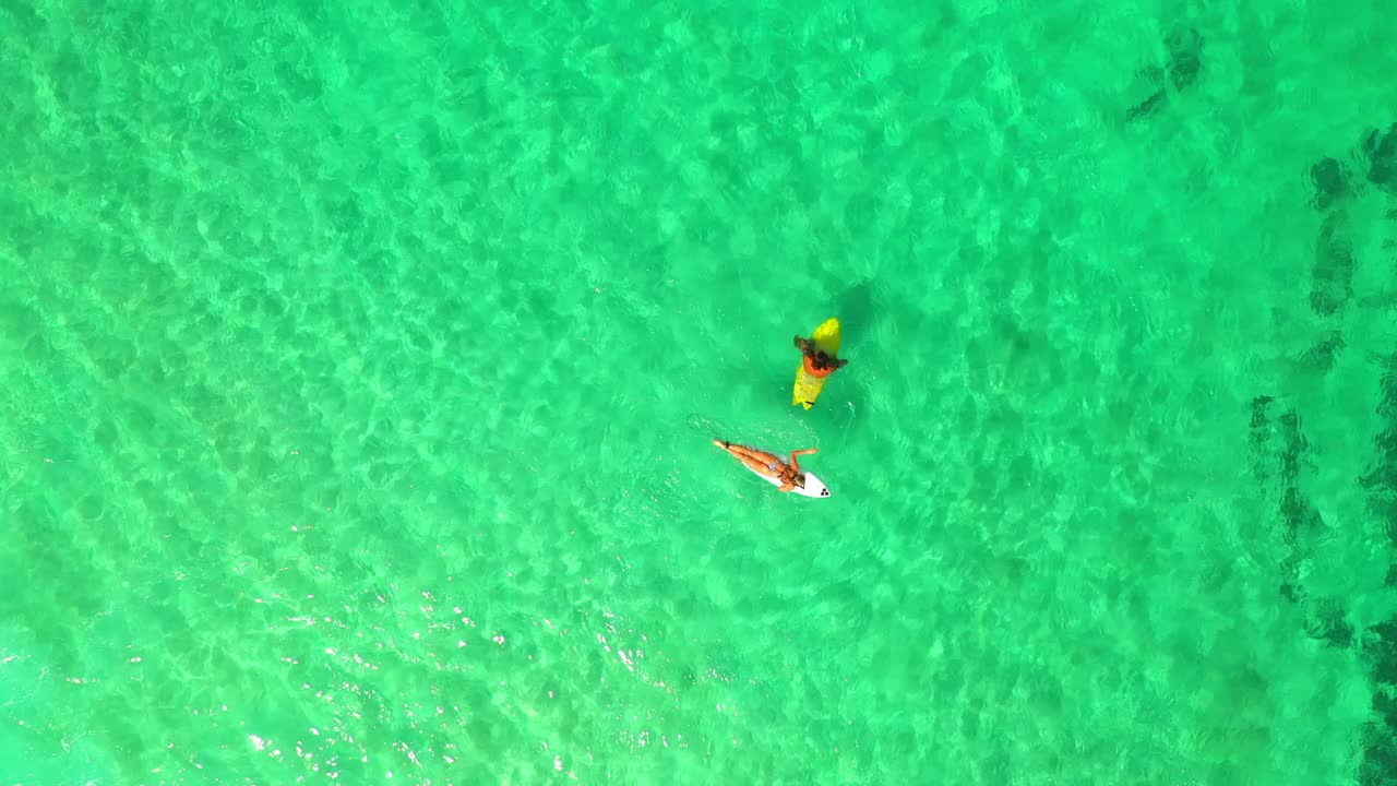 在阳光灿烂的日子里，夏威夷瓦胡岛，蓝色大海冲浪板上的男人和女人的航拍俯视图视频素材