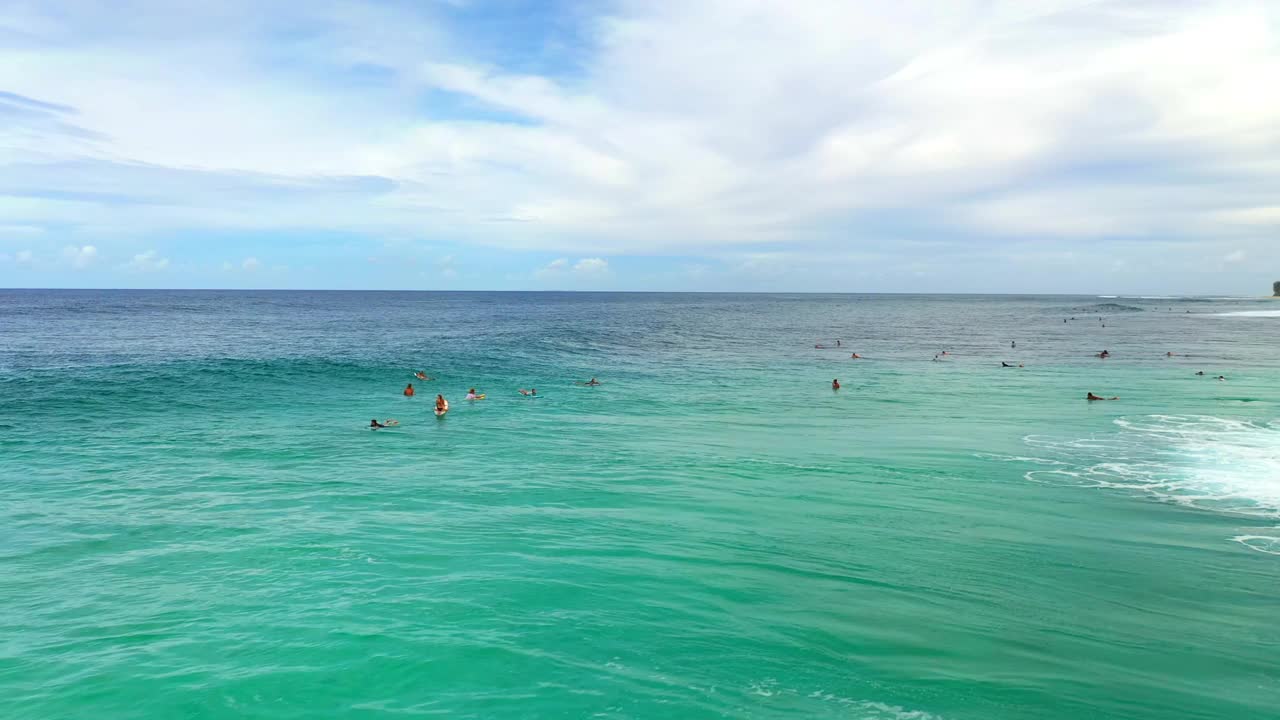 人们用冲浪板在蔚蓝的大海中享受多云的天空的空中向前拍摄-夏威夷瓦胡岛视频素材