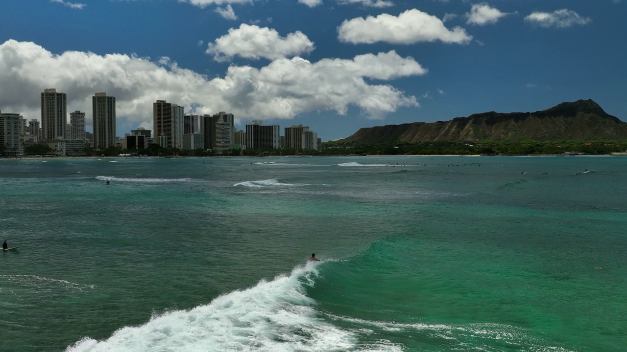 空中慢动作向前拍摄冲浪者在海上冲浪的建筑和瓦胡岛度假期间-夏威夷怀基基视频素材