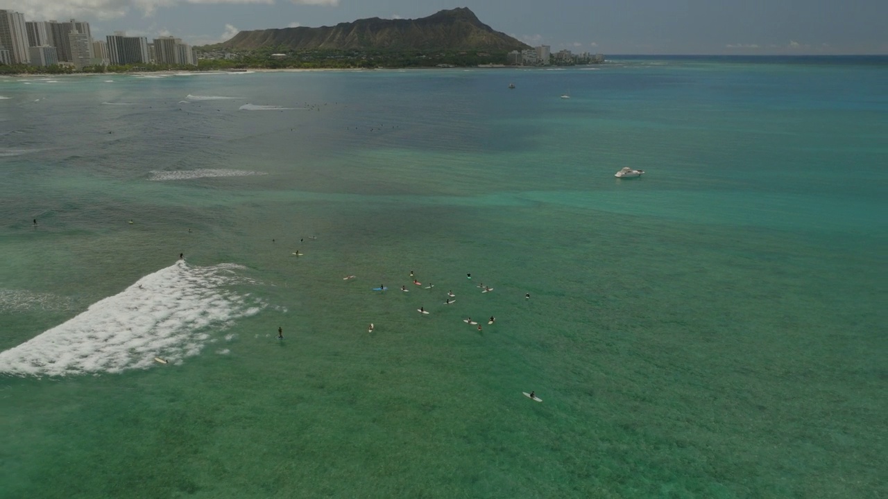 空中倾斜镜头的人与冲浪板在海上瓦胡岛对多云的天空-怀基基，夏威夷视频素材