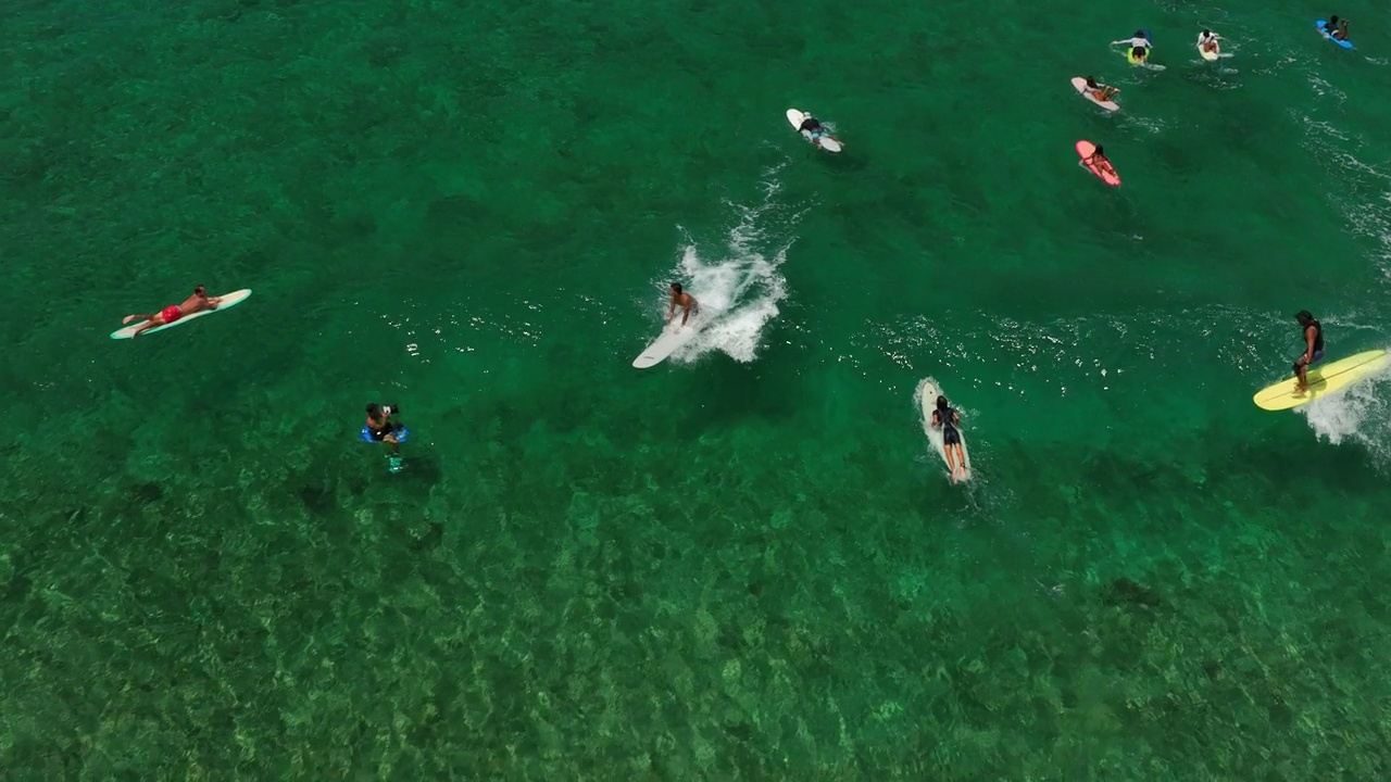 空中慢动作向后拍摄的男性冲浪者与冲浪板游泳由游客在海上度假-威基基，夏威夷视频素材