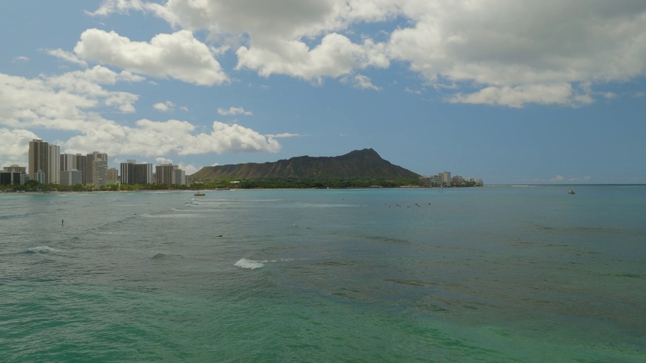 游客在瓦胡岛冲浪的航拍镜头，无人机在云层下飞越海洋-夏威夷威基基视频素材