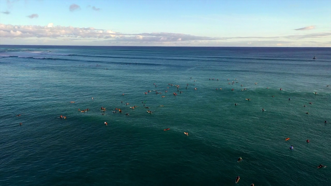 空中平移拍摄的人与冲浪板在蔚蓝的大海下多云的天空-瓦胡岛，夏威夷视频素材