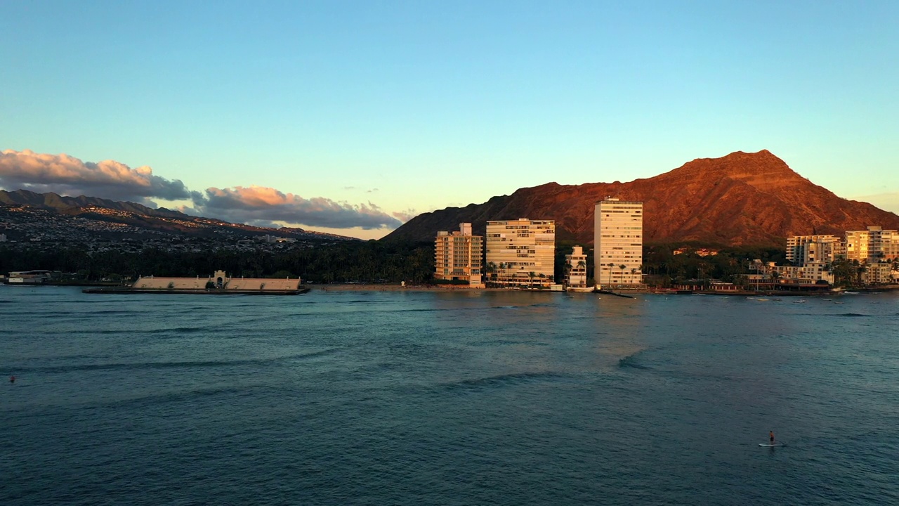 在日落期间，海滩上的酒店建筑航拍蓝色的海-夏威夷瓦胡岛视频素材