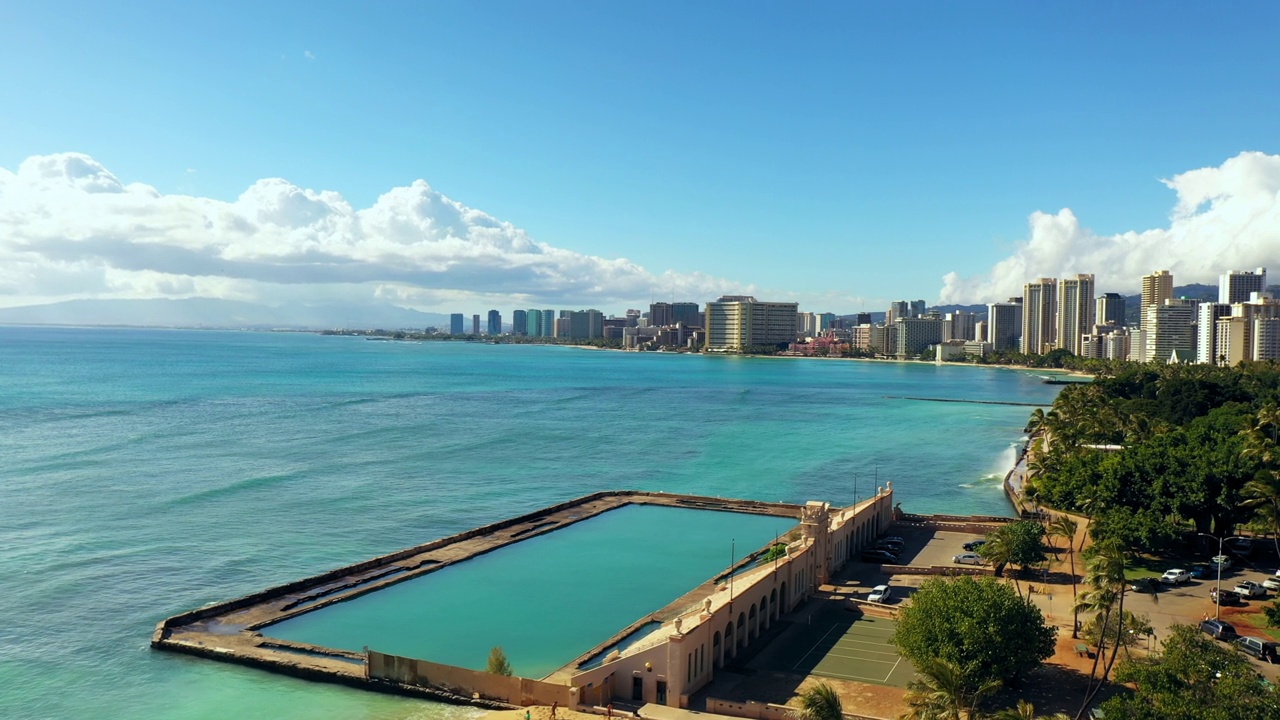 空中向前拍摄的游泳池与蓝色的大海对建筑物在阳光灿烂的一天-瓦胡岛，夏威夷视频素材