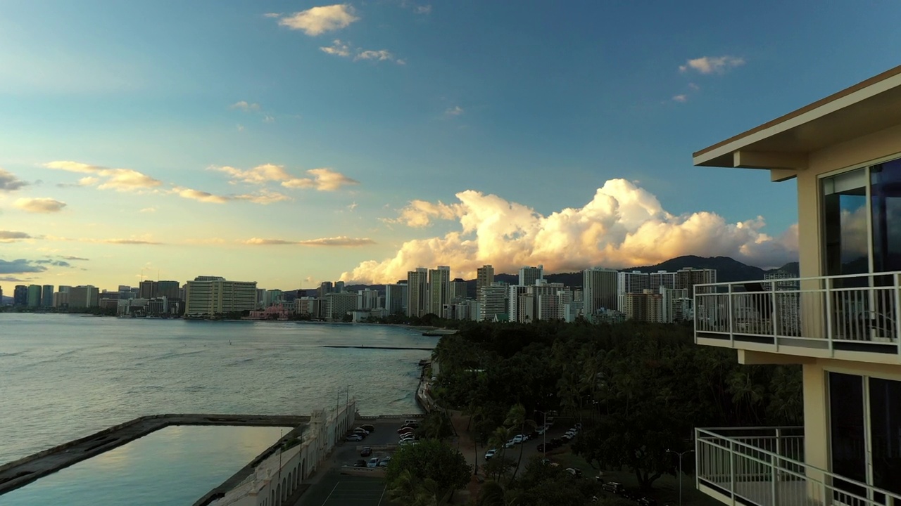 空中向前拍摄的树木和建筑物在海上对多云的天空日落-瓦胡岛，夏威夷视频素材