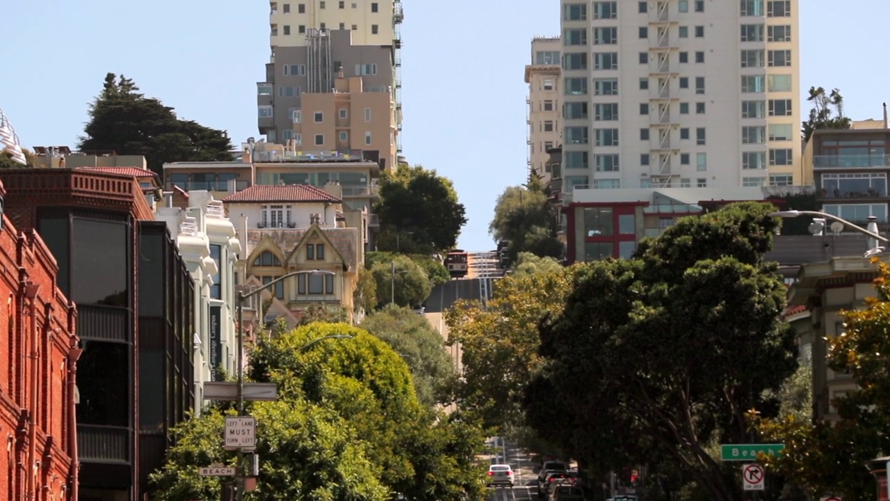 在阳光明媚的日子里，车辆在树木和建筑物之间的道路上移动-旧金山，加利福尼亚视频素材