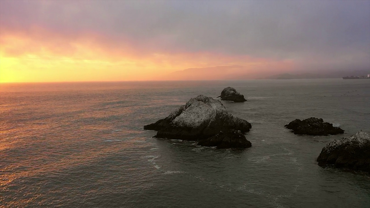 空中平移拍摄的大岩石在海浪的海洋下云日落-旧金山，加利福尼亚视频素材