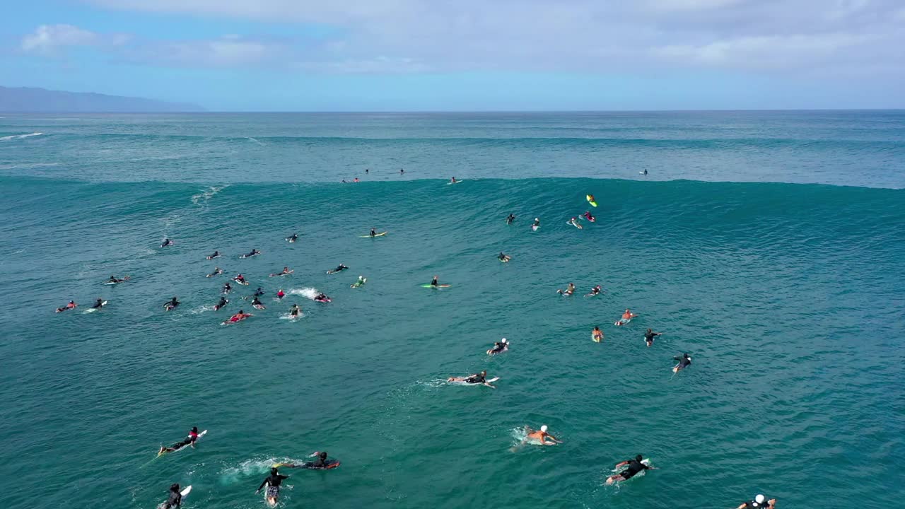 在多云天空下的海滩上冲浪的冲浪者的空中平移镜头-夏威夷威基基视频素材