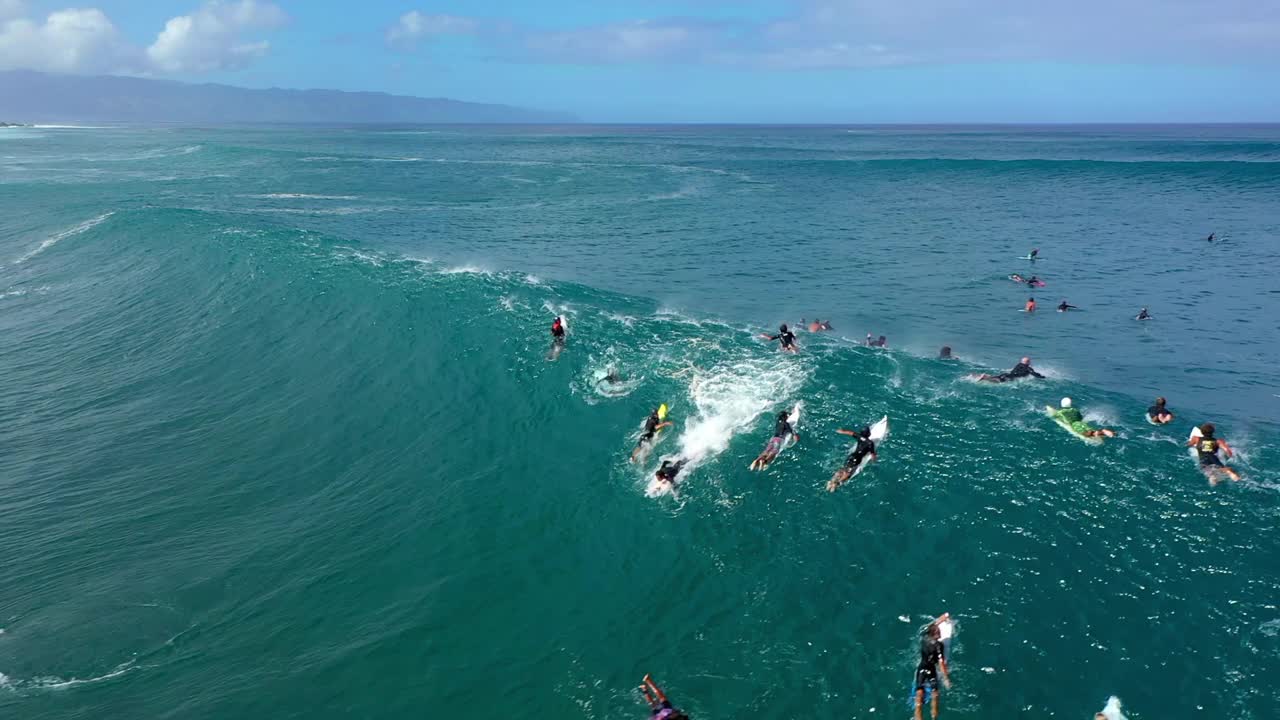 空中平移拍摄的人们冲浪，而彩虹从海浪中发射在度假期间-夏威夷威基基视频素材