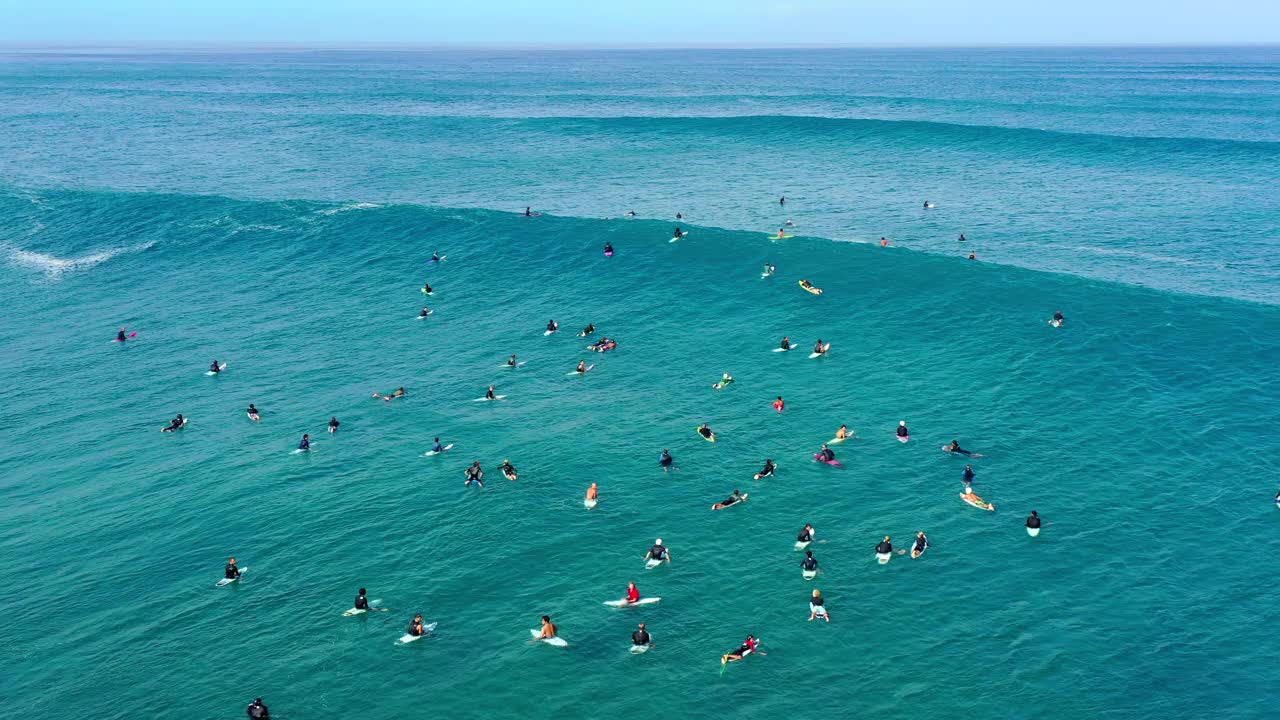 空中向后拍摄的人游泳与冲浪板在海浪在大海-威基基，夏威夷视频素材