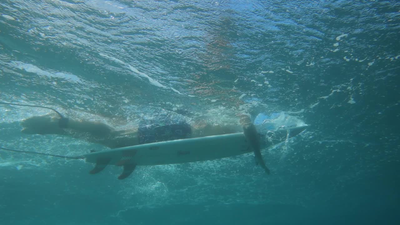 从水下看到的男性冲浪者用冲浪板游泳的慢动作镜头——夏威夷檀香山视频素材