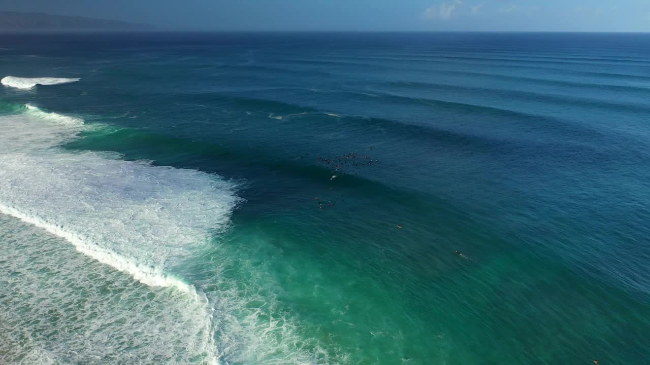 航拍的人们在波浪状的海里游泳，无人机在阳光灿烂的日子里向前飞行——夏威夷瓦胡岛视频素材