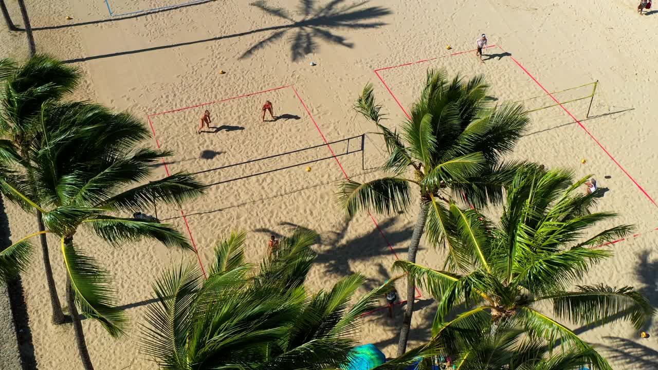 空中平移拍摄的女性朋友在阳光灿烂的一天在海滩上打排球——夏威夷瓦胡岛视频素材