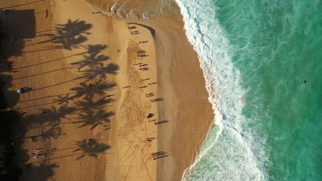 人们站在绿松石色的海岸线上，无人机在夏威夷瓦胡岛的海滩上空飞行视频素材