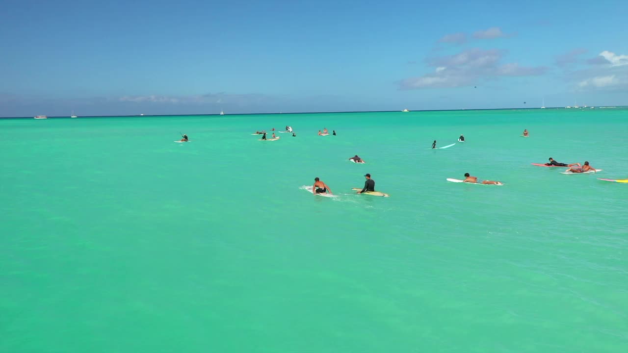 空中拍摄的游客与冲浪板游泳在绿海云下-瓦胡岛，夏威夷视频素材