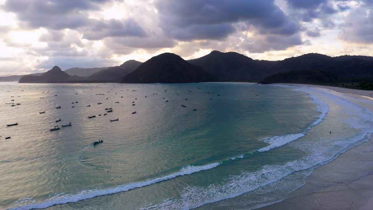 空中向后上升拍摄的船在海上对山在多云的天空下-龙目岛，印度尼西亚视频素材