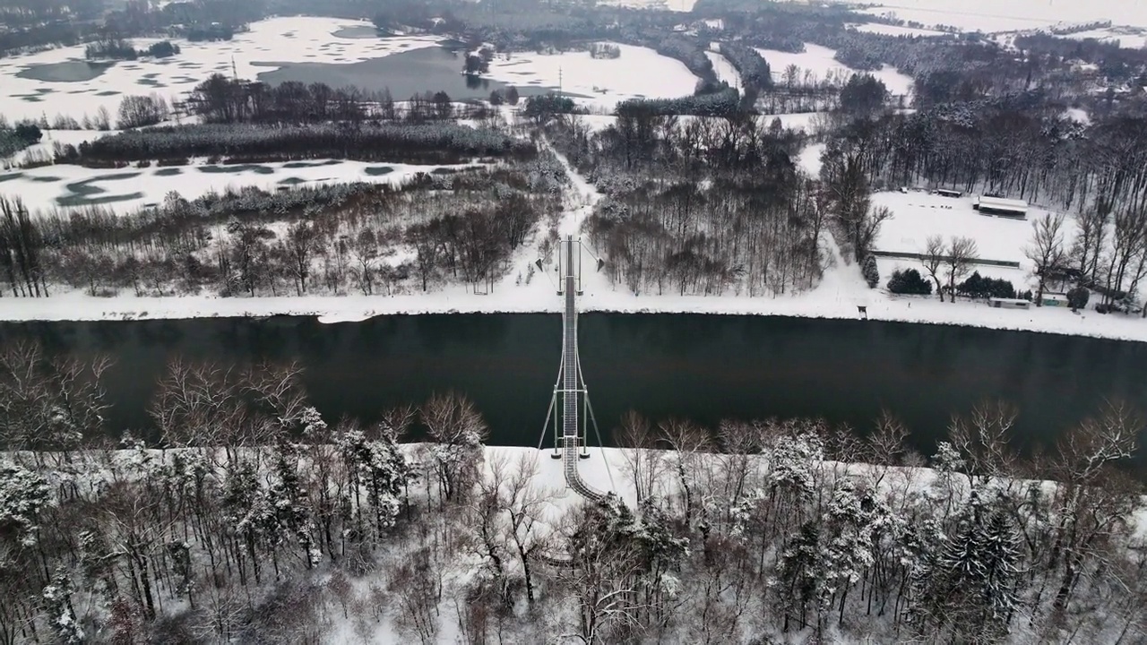 有美丽河岸的河流和一座桥，位于白雪覆盖的森林附近视频素材