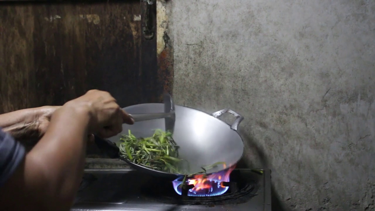 在厨房用大火在平底锅里炒菠菜，亚洲泰式美食，泰国流行的街头小吃菜单。视频素材