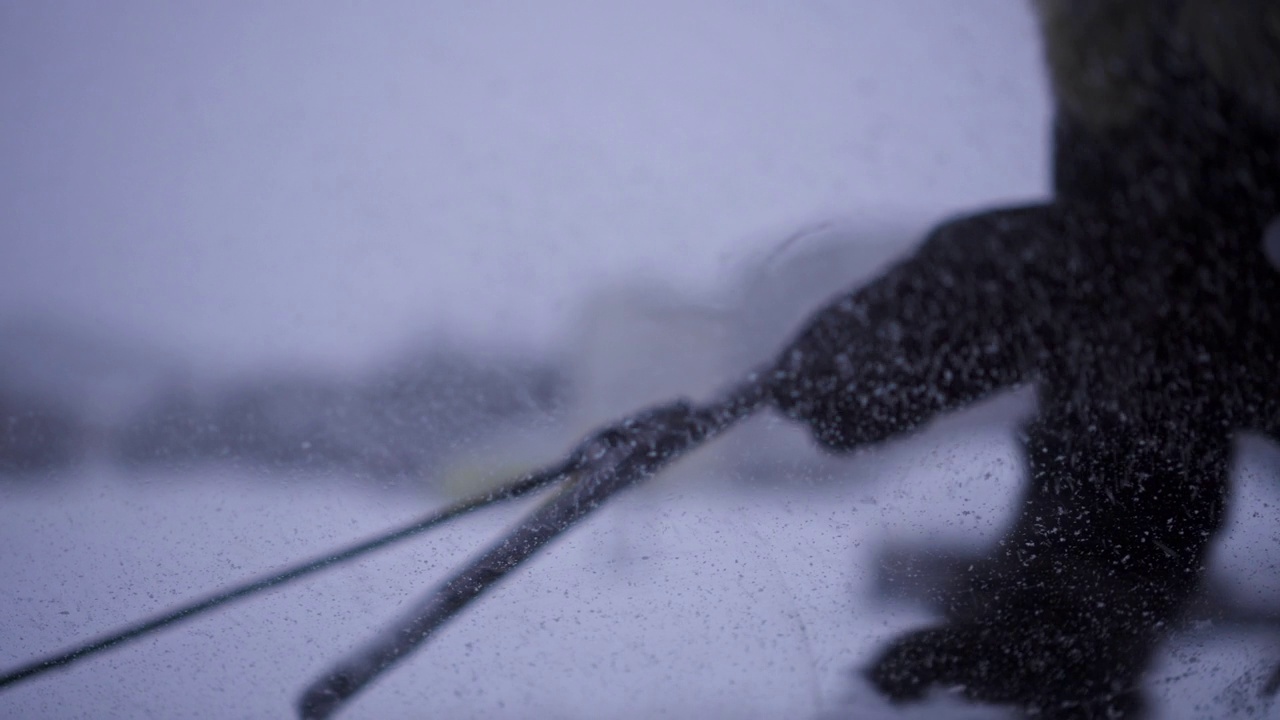 女子在雪中清洗汽车挡风玻璃。视频素材