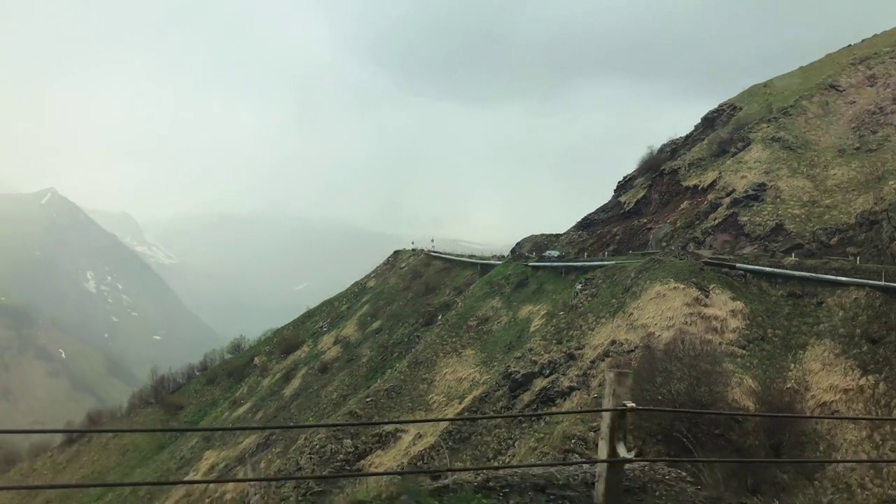 在一条山路上，从汽车上可以看到白雪覆盖的山峰。视频素材