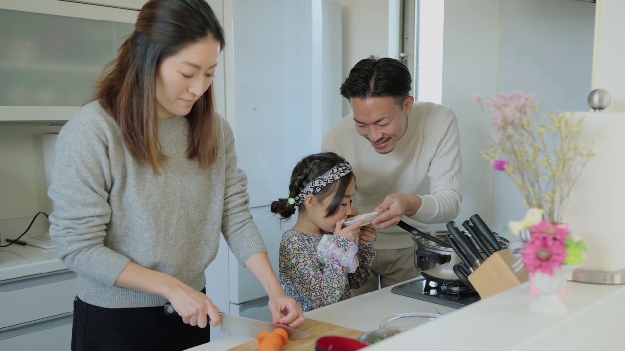 小女孩在她父母做饭的厨房里品尝。视频素材