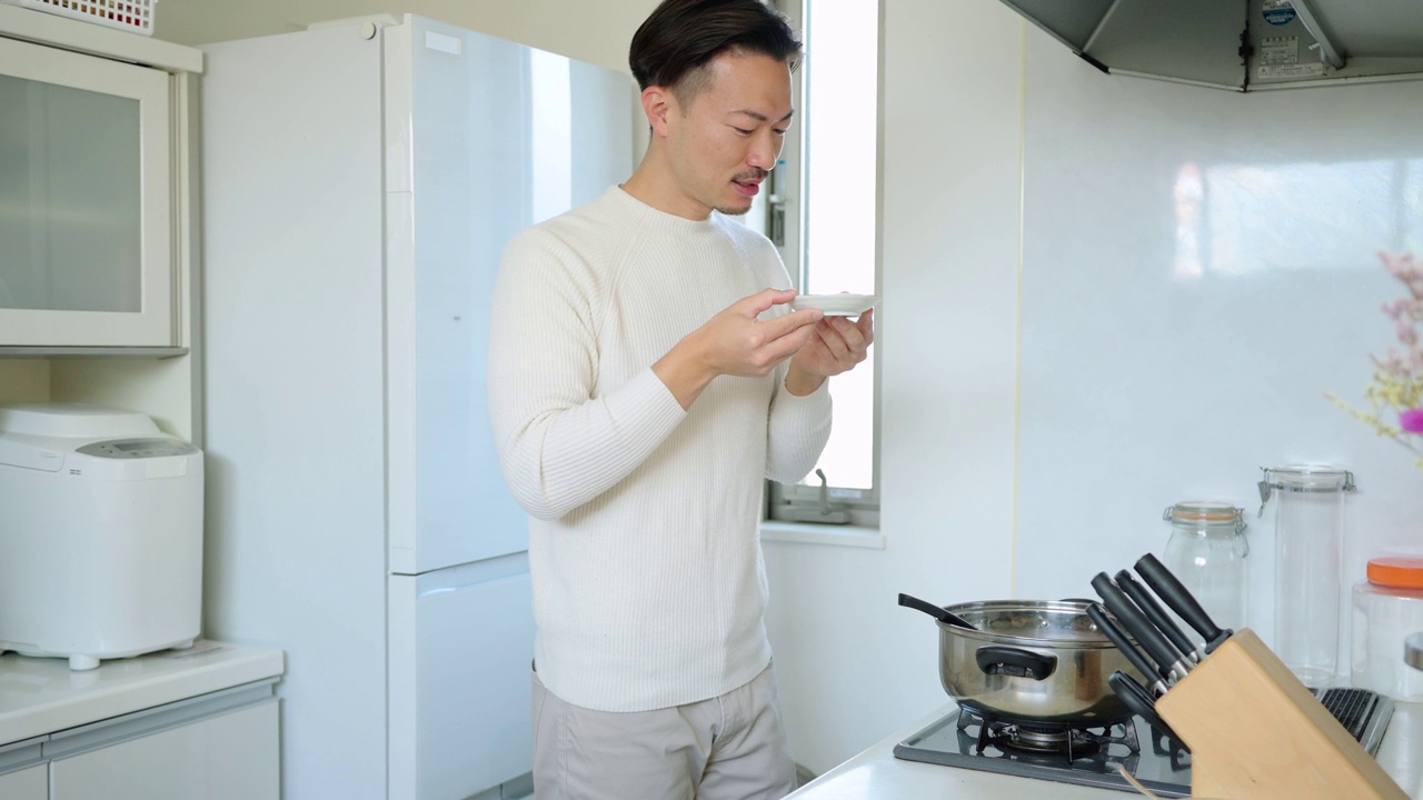 年轻人一边在厨房做饭一边品尝食物。视频素材