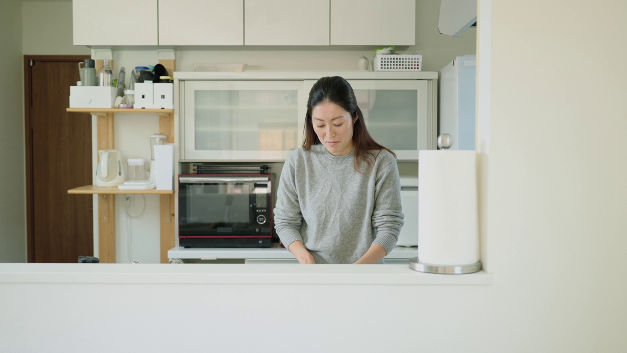 年轻女子一边在厨房做饭一边和家人聊天视频素材