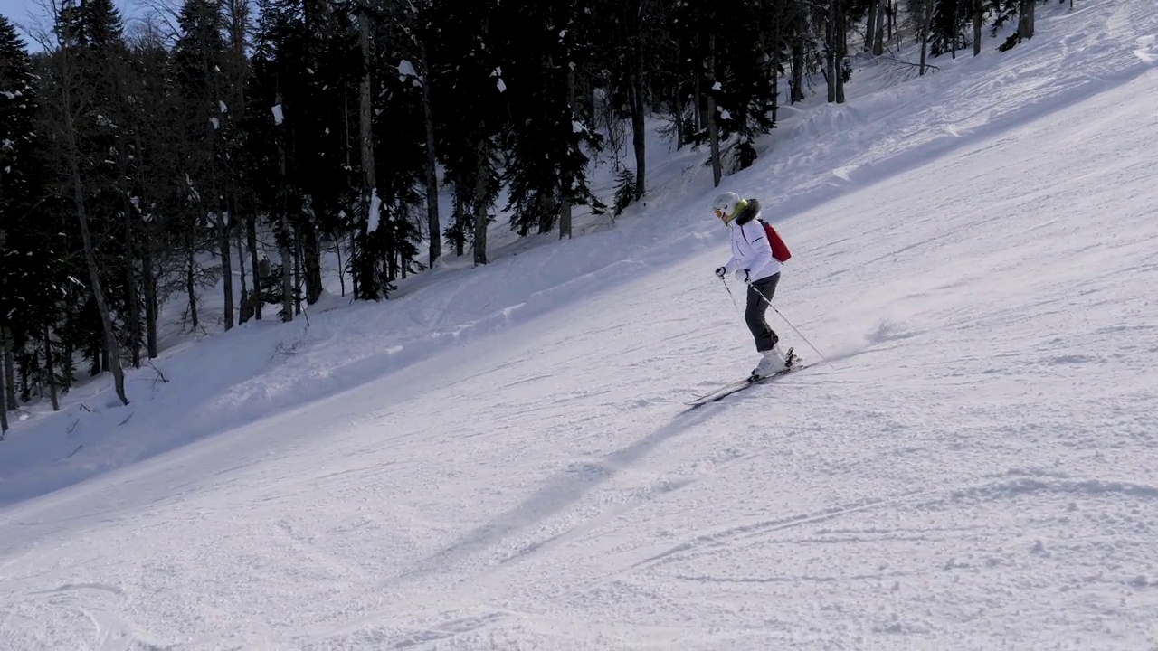 滑雪者在阳光明媚的冬日滑下山坡视频素材