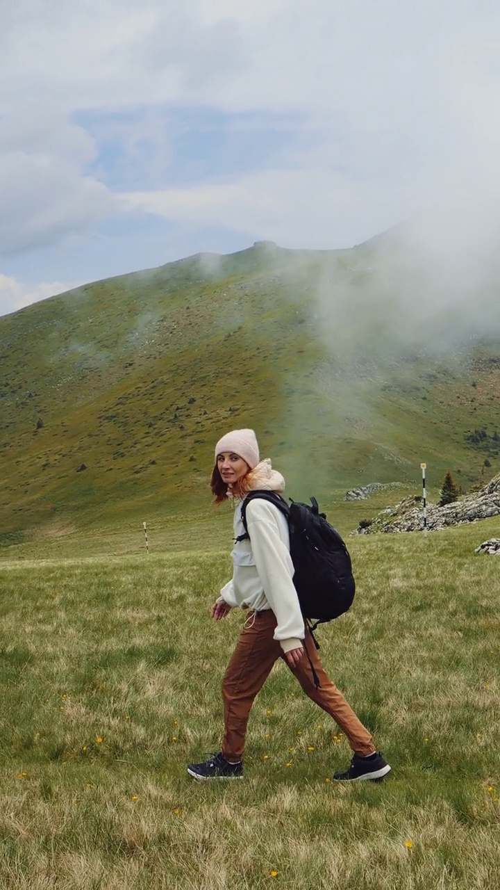 女人走在绿草在山上视频素材