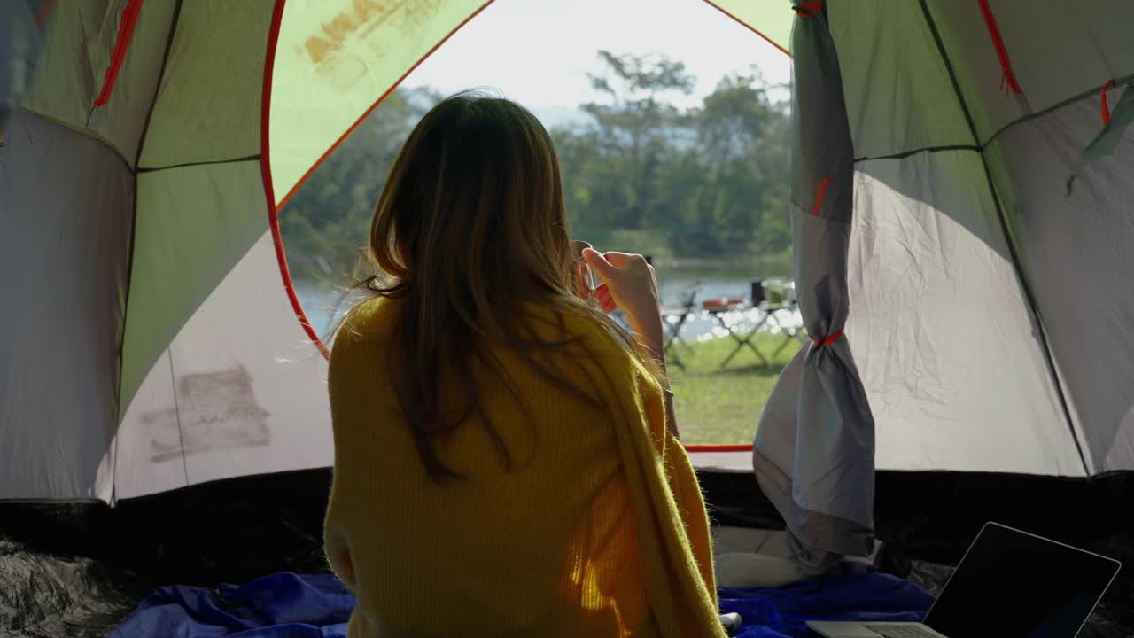 亚洲女子在帐篷里独自啜饮咖啡，在寒冷的早晨氛围中，自由概念，旅行者，旅行，放松视频素材