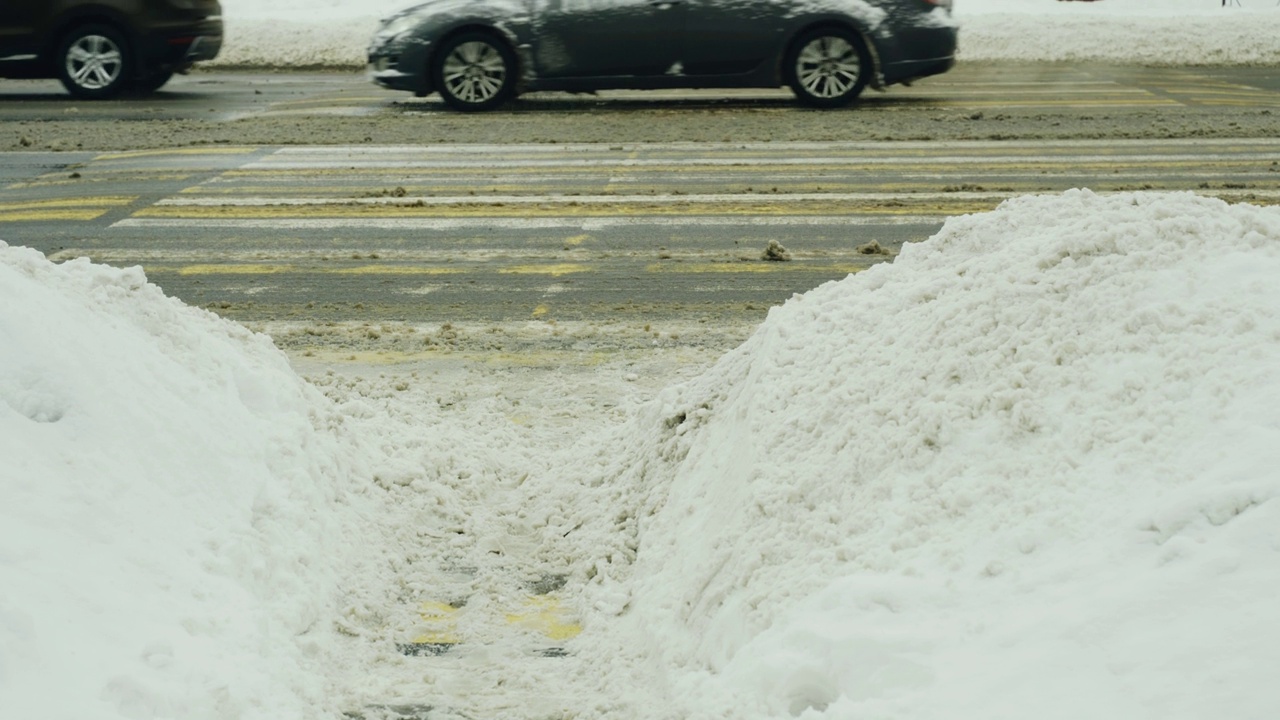 行人十字路口的景色，冬天汽车在上面行驶，穿过雪堆视频素材