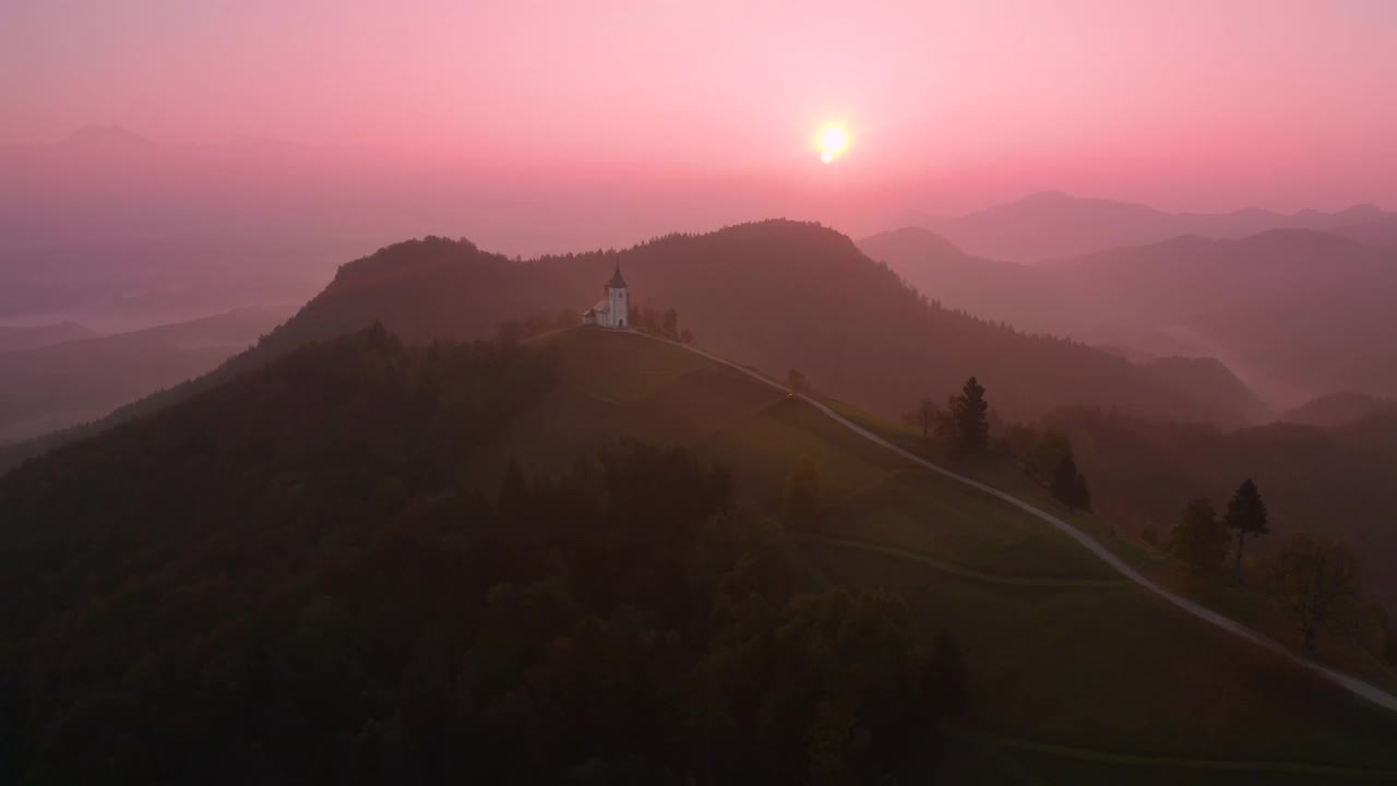 黎明时分，斯洛文尼亚山上美丽的小教堂的无人机鸟瞰图。美丽的秋日晨景视频下载