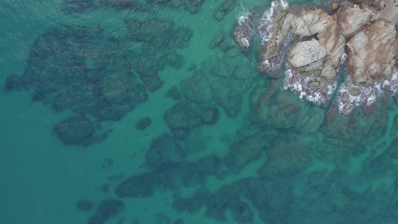 从无人机鸟瞰海岸上的岩石和蓝绿色的水视频下载