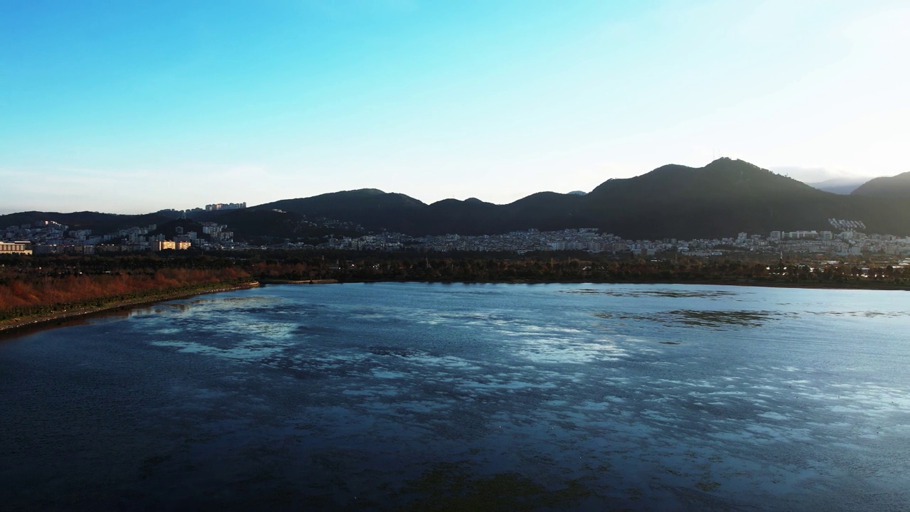 日落时分，伊兹密尔因奇拉尔蒂城市森林泻湖的空中全景。背景为山脉和城市景观视频素材