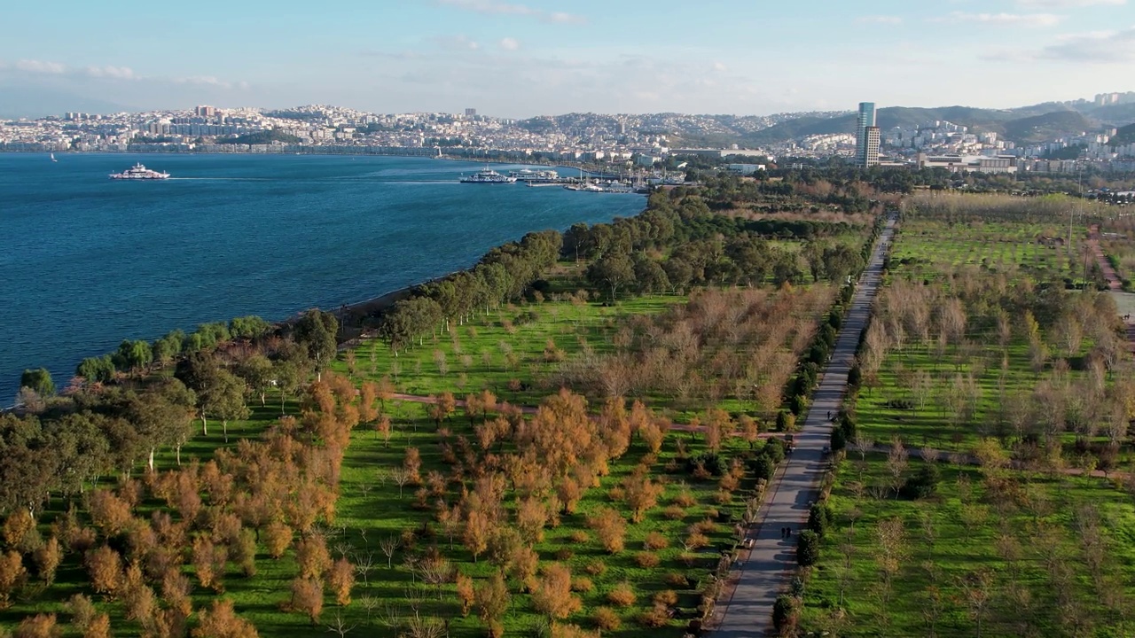 空中俯瞰伊兹密尔湾的因吉拉尔蒂城市森林和城市景观，海上的渡轮和帆船视频下载