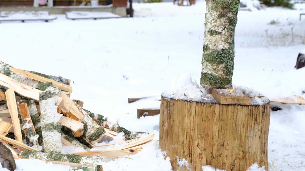 一个人在冬天的雪地里用斧头劈柴。替代供暖，木材采伐，能源危机视频素材