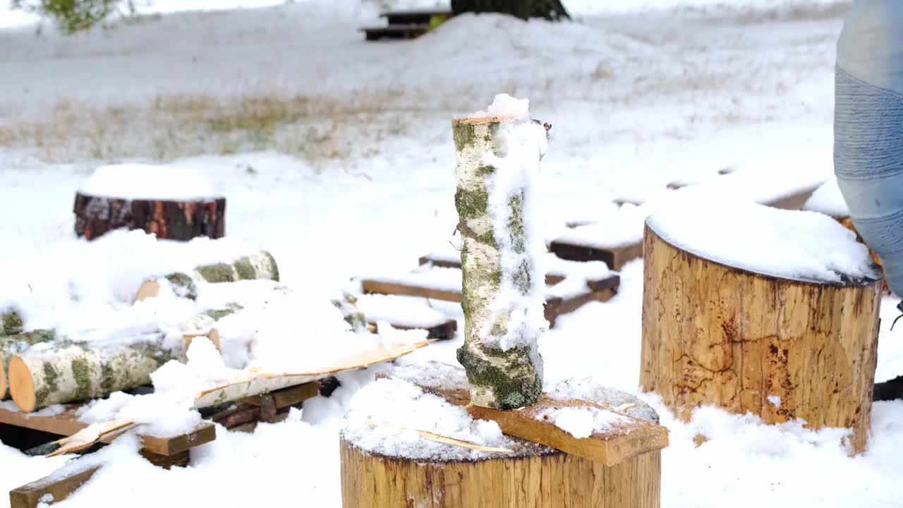 一个人在冬天的雪地里用斧头劈柴。替代供暖，木材采伐，能源危机视频素材