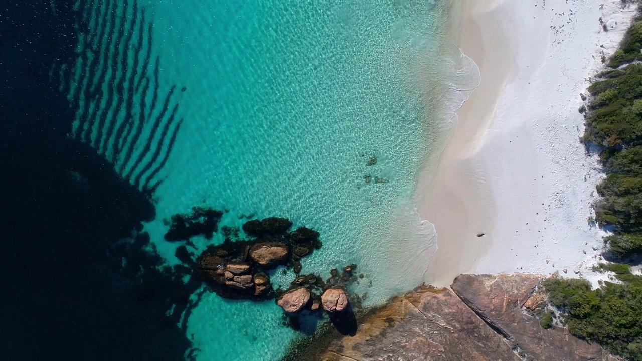 盘旋在温和的波浪上，在原始的清澈的海湾水与白色的沙子和岩层视频素材