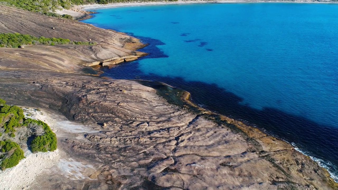 漂浮在海岸场景的原始清澈海湾的水与白色的沙子和岩层视频素材