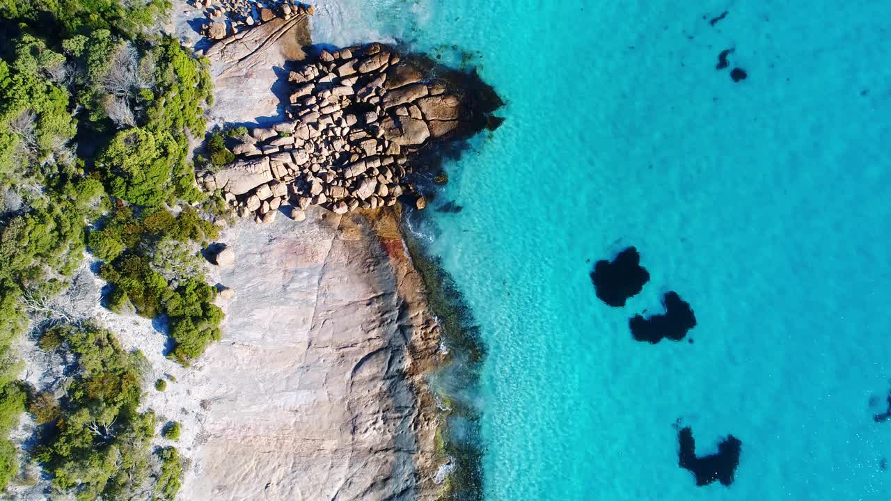 上面温和的海浪拍打着原始清澈的海湾，有白色的沙子和岩石视频素材