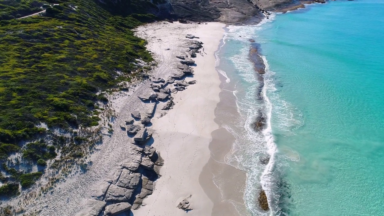 上面温和的海浪拍打着原始清澈的海湾，有白色的沙子和岩石视频素材