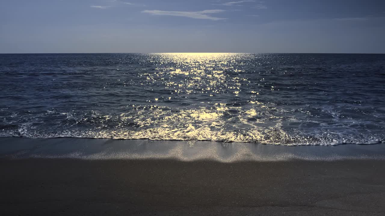 月光映在海面上，柔和的波浪是拍打着海滩的波光粼粼视频下载