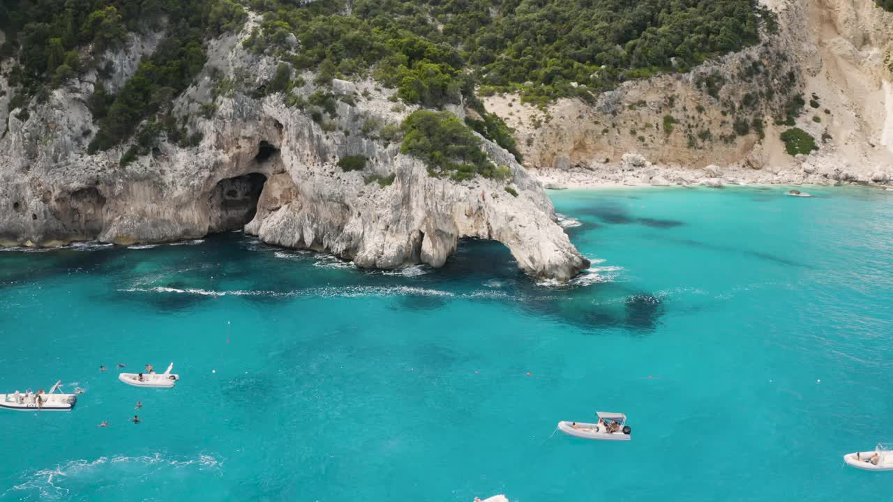 飞过美丽的海洞和清澈的蓝色翡翠水与船的顶部视图。夏季海景鸟瞰图。意大利撒丁岛视频下载