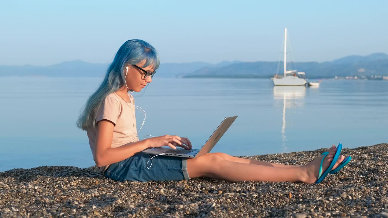 海滩上拿着笔记本电脑的严肃女孩。视频素材