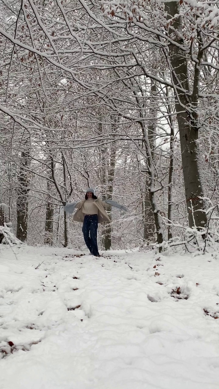 快乐的女人在白雪覆盖的冬季森林纺纱视频素材